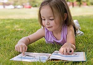 一位小女孩在草地上看书